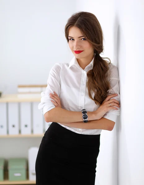 Attraktive Geschäftsfrau steht an Wand im Büro — Stockfoto