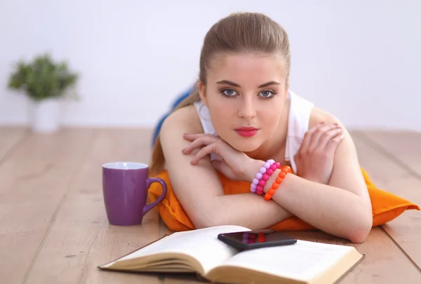 Lachende jonge vrouw liggend op een witte vloer met kussen — Stockfoto