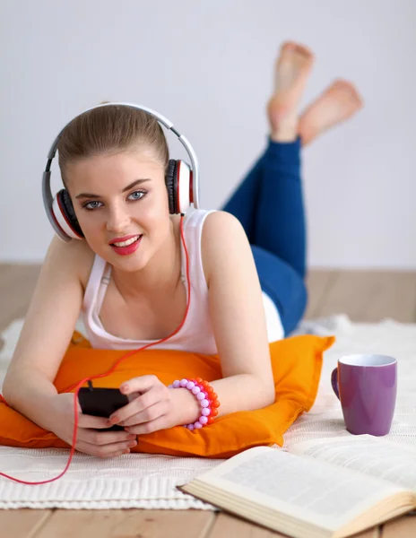 Młoda kobieta, leżąc na podłodze i słuchać muzyki — Zdjęcie stockowe