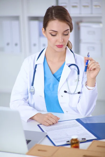 Médica mulher sentada na mesa e trabalhando em um laptop — Fotografia de Stock