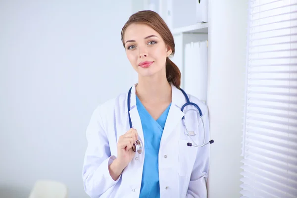 Femme médecin est debout près de la fenêtre avec les bras croisés, isolé — Photo