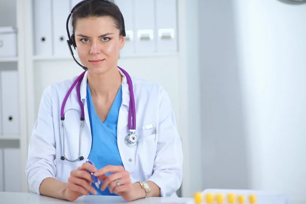 Retrato de la joven doctora en bata blanca en el ordenador usando el teléfono —  Fotos de Stock