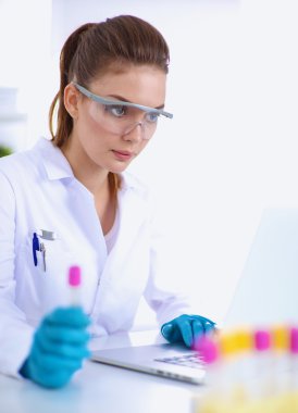 Kadın araştırmacı, beyaz şişeler ve şişelerle çevrili.