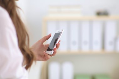 İş kadını ofiste akıllı telefonla mesaj gönderiyor.