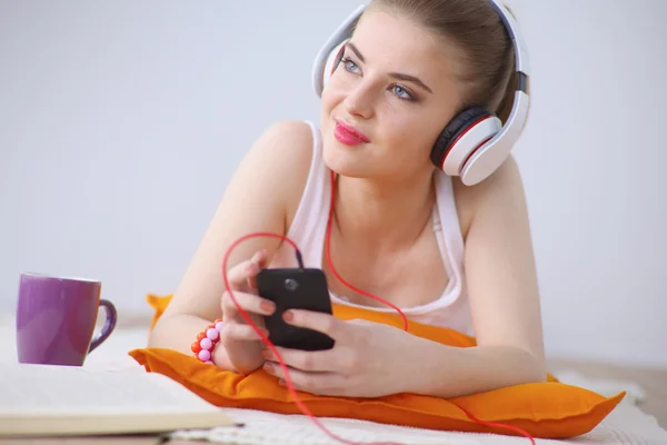 Mujer joven tumbada en el suelo y escuchando música — Foto de Stock