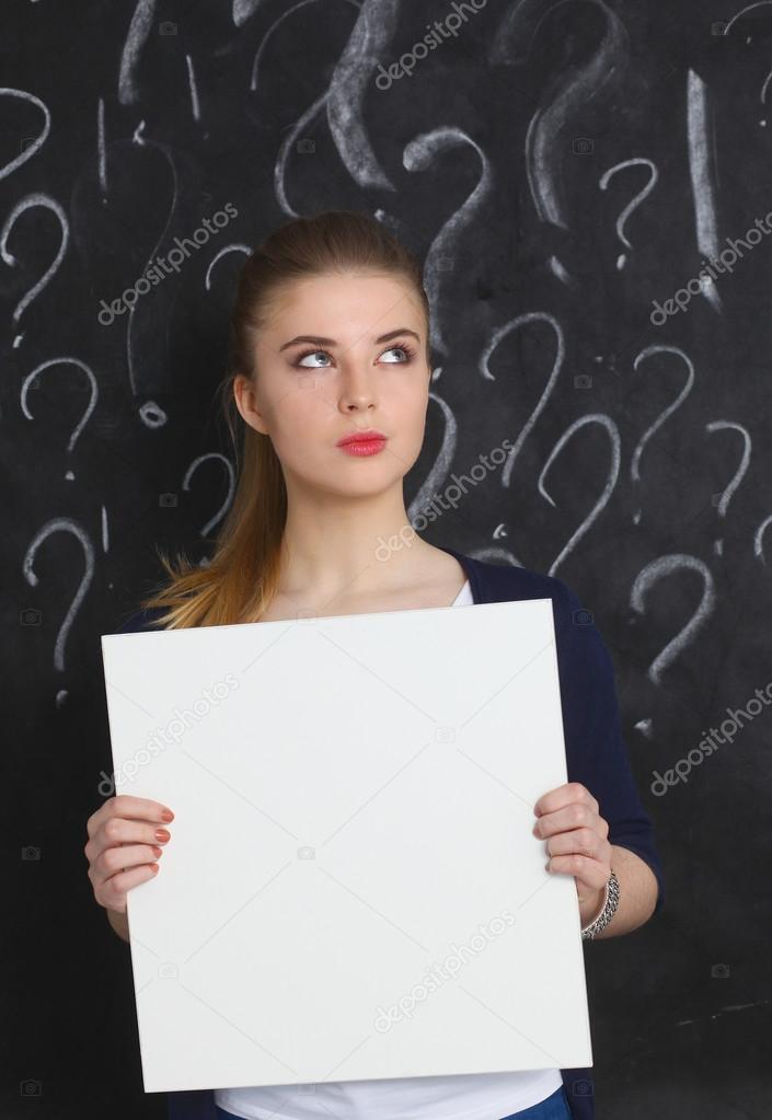 Young girl with question mark holding a blank on  gray background