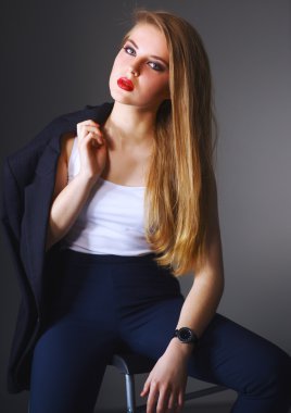 Genç bir kadın sandalyede oturuyor.