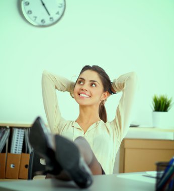 İş kadını ellerini başının arkasına koyup bir ofis sandalyesinde oturuyor.