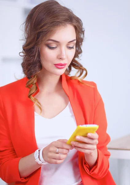 Beautiful businesswoman using cell phone standing in office — Stock Photo, Image