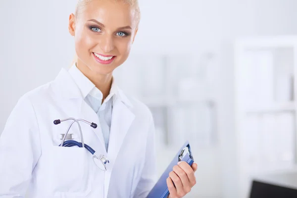 Lächelnde Ärztin mit Ordner in Uniform steht im Krankenhaus — Stockfoto