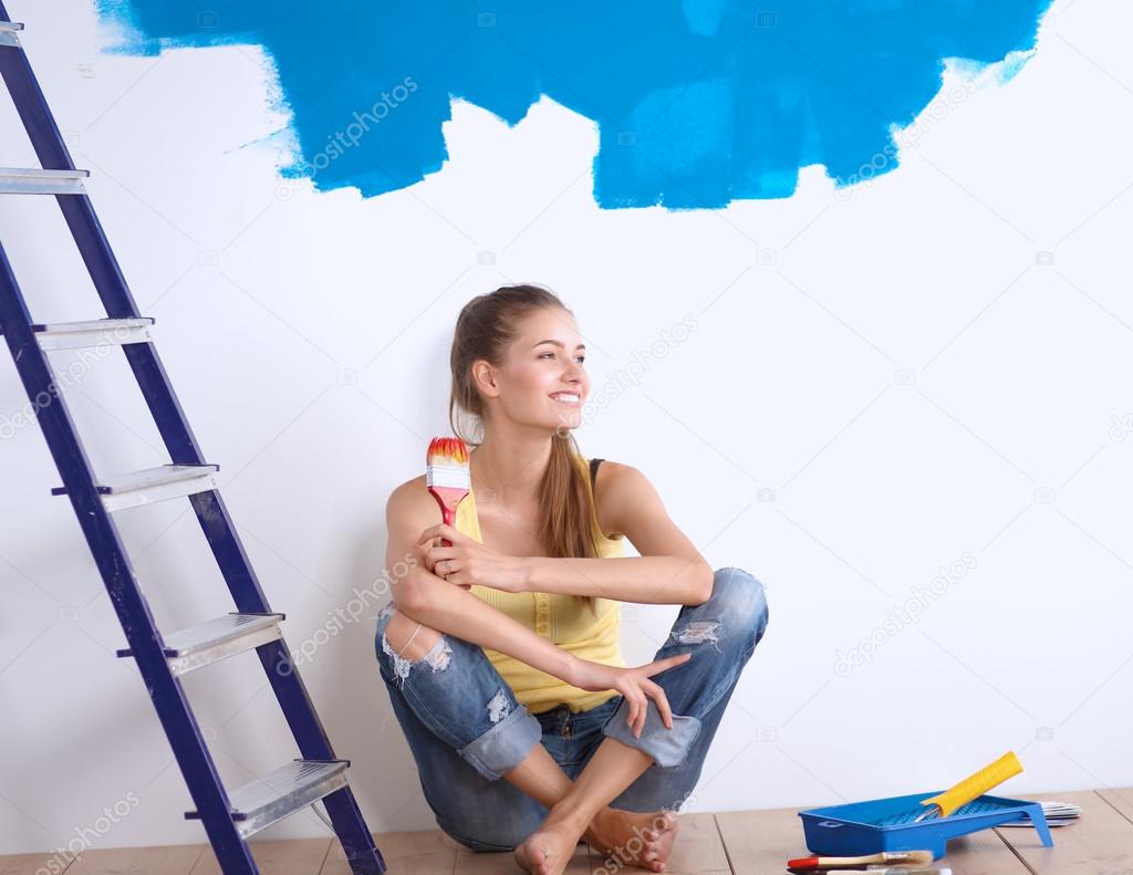 Portrait of female painter sitting on floor near wall after painting.