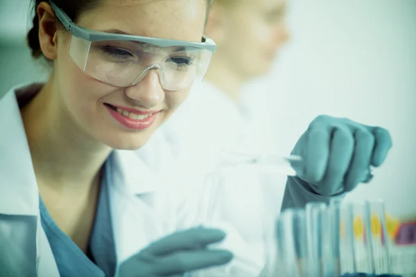 Woman researcher is surrounded by medical vials and flasks, isolated on white — Stock Photo, Image