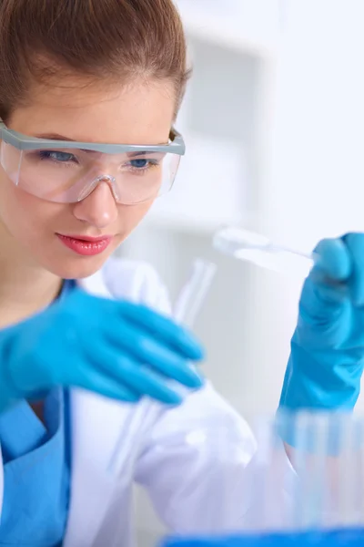 Woman researcher is surrounded by medical vials and flasks, isolated on white background — Stock Photo, Image