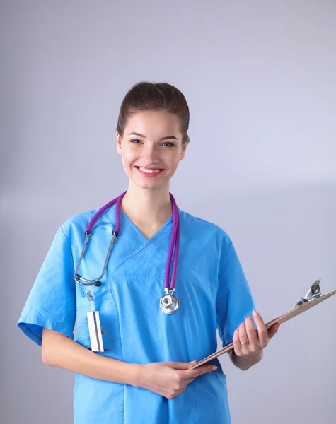 Médico sonriente con una carpeta en uniforme de pie en el hospital — Foto de Stock