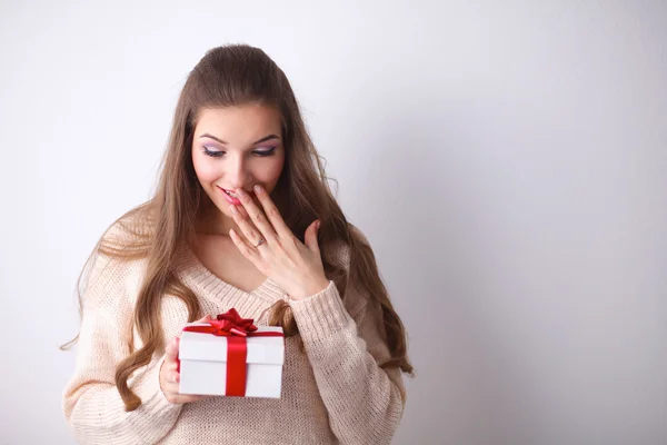 Молодая женщина счастливая улыбка держать подарочную коробку в руках, стоя на сером фоне — стоковое фото
