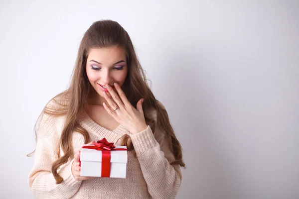 Young woman happy smile hold gift box in hands,standing over grey background — Stock Photo, Image