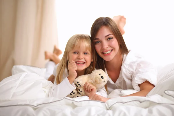 Woman and young girl lying in bed smiling — Stock Photo, Image