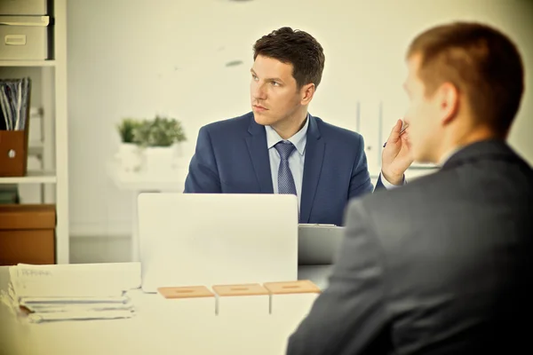 Zakenman of manager die op kantoor tegen zijn bureau staat — Stockfoto