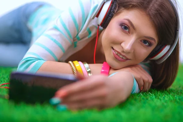 Hermosa joven mujer haciendo selfie por su teléfono mientras se encuentra en la hierba verde —  Fotos de Stock