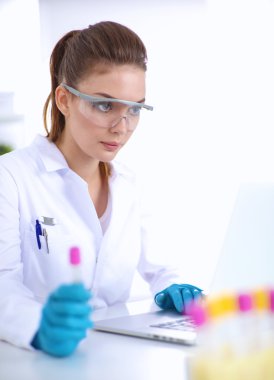 Kadın araştırmacı, beyaz şişeler ve şişelerle çevrili.