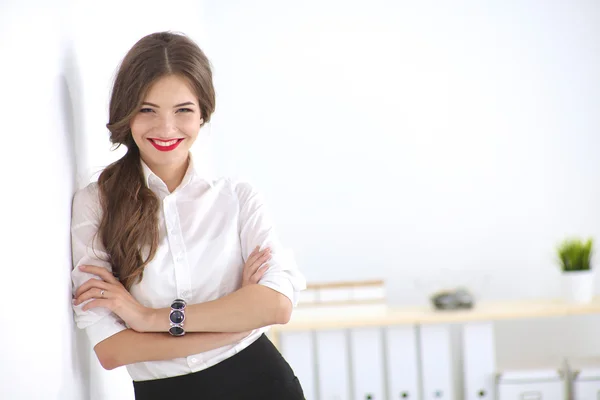 Attractive businesswoman standing near wall in office — Stock Photo, Image