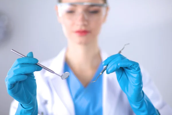 Dentista feminino atraente com ferramentas, de pé sobre cinza — Fotografia de Stock