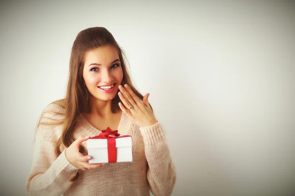 Mujer joven sonrisa feliz celebrar caja de regalo en las manos, de pie sobre fondo gris —  Fotos de Stock