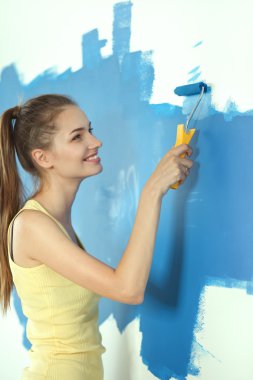 Güzel genç bir kadın duvar boyuyor.