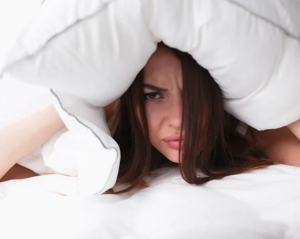 Kvinna liggande på sängen och stänga öronen med kudde — Stockfoto