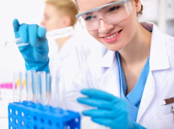 Woman researcher is surrounded by medical vials and flasks, isolated on white background — Stock Photo, Image