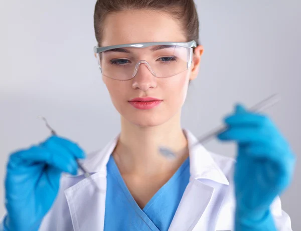 Dokter gigi wanita yang menarik dengan peralatan, berdiri di atas latar belakang gay — Stok Foto