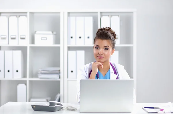 Vrouwelijke arts zit op het bureau en werkt een laptop in het ziekenhuis — Stockfoto