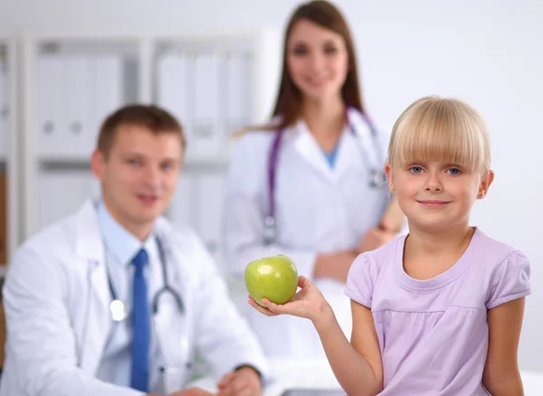 Η έννοια του παιδιού και της ιατρικής - γυναίκα γιατρός δίνει ένα μήλο στο κοριτσάκι — Φωτογραφία Αρχείου