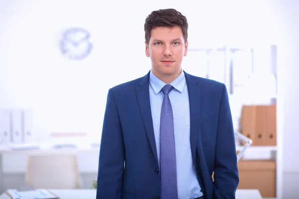 Business man or manager standing against his desk at office — Stock Photo, Image