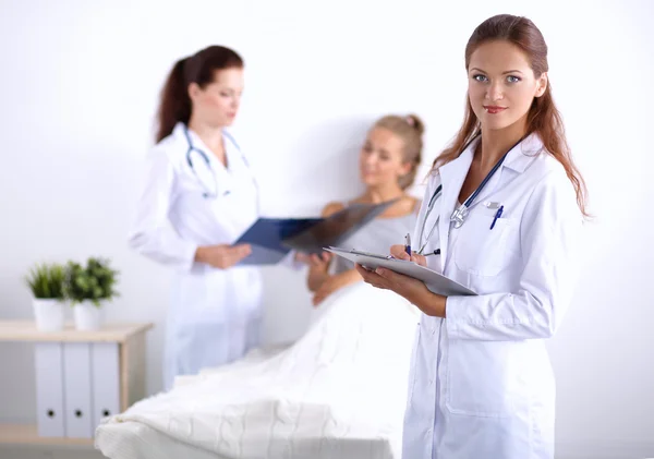 Médico sonriente con una carpeta en uniforme de pie en el hospital — Foto de Stock