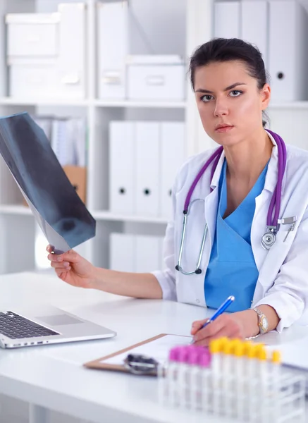 Jeune femme médecin étudiant l'image radiographique assise sur le bureau — Photo
