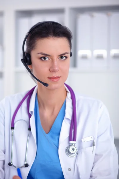 Dokter draagt een headset zittend achter een bureau met laptop — Stockfoto