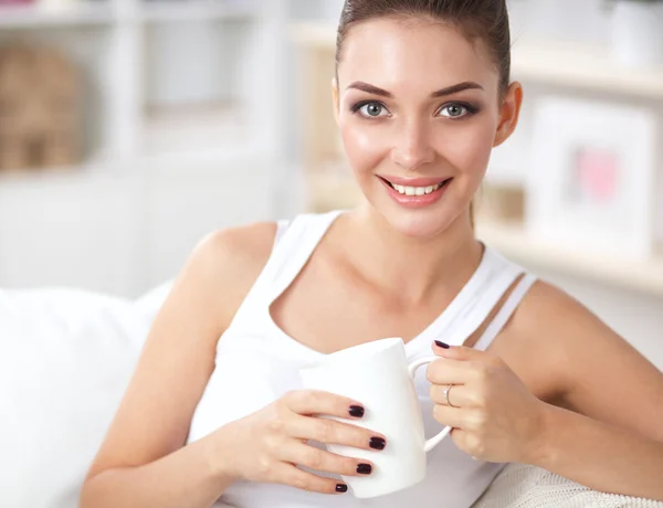 Retrato de la hermosa mujer con una taza en el sofá en casa —  Fotos de Stock