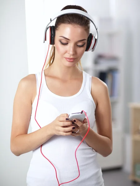 Mujer con auriculares escuchando música de pie en casa — Foto de Stock