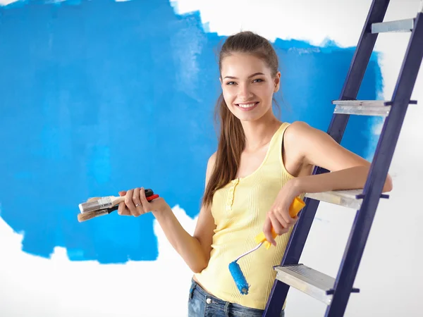 Feliz hermosa mujer joven haciendo pintura de pared, de pie cerca de la escalera —  Fotos de Stock