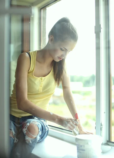 Woman painting wall of an apartment with a paintbrush carefully finishing off around  window frame — Stock Photo, Image