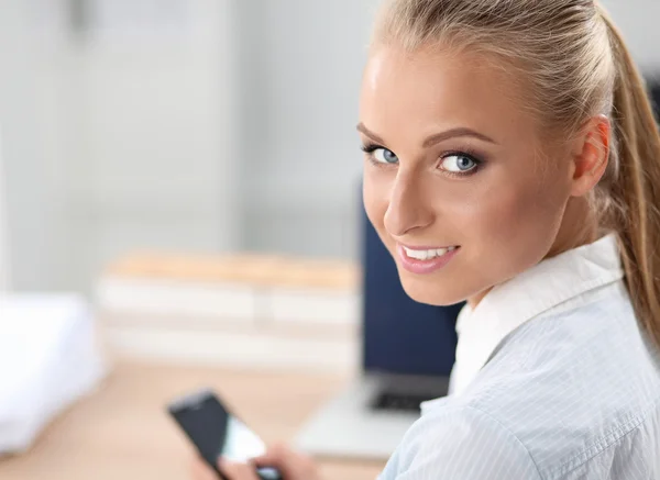 Businesswoman sending message with smartphone sitting in the office — Stock Photo, Image