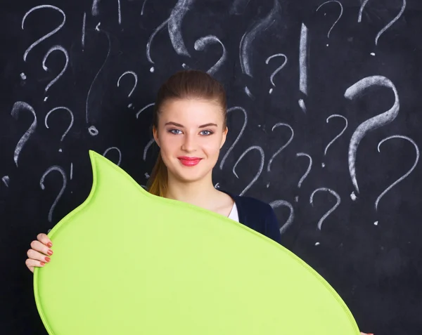 Chica joven con signo de interrogación sosteniendo un espacio en blanco sobre un fondo gris — Foto de Stock