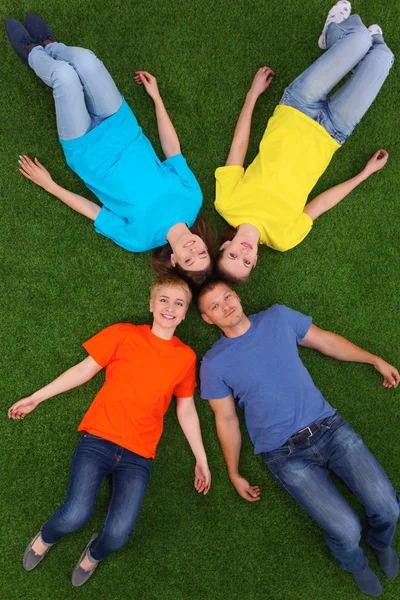 Grupo de jóvenes acostados sobre hierba verde — Foto de Stock