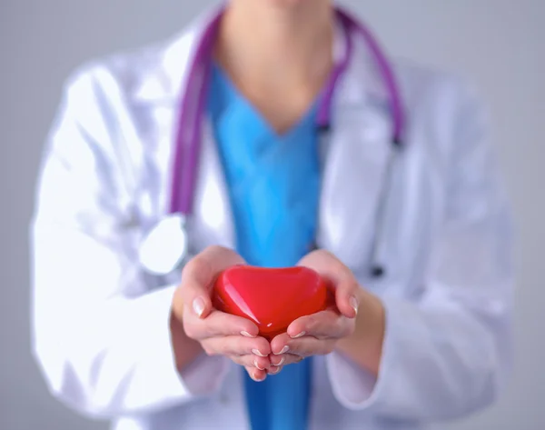 Mujer joven doctora sosteniendo un corazón rojo, parada en el hospital — Foto de Stock