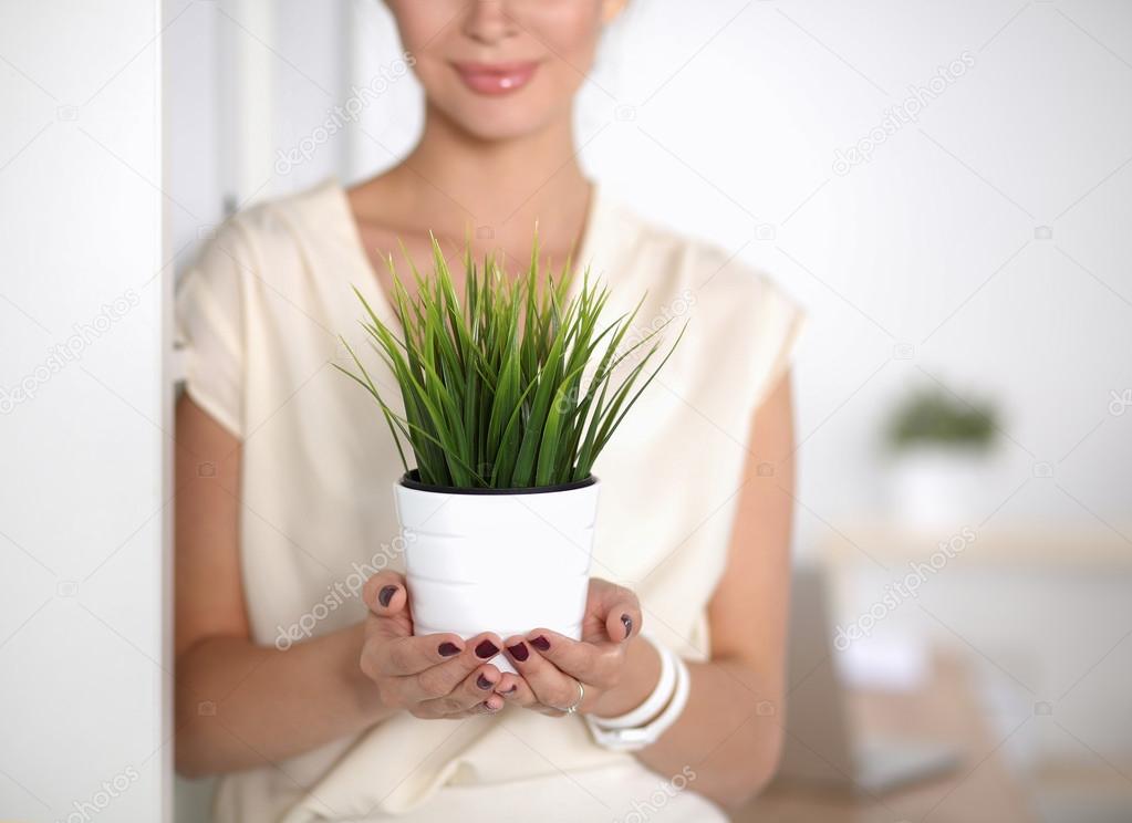 Beautiful woman holding pot with a plant