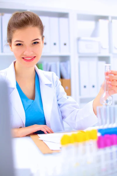 Kvinnlig forskare är omgiven av medicinska flaskor och kolvar, isolerade på vit bakgrund — Stockfoto