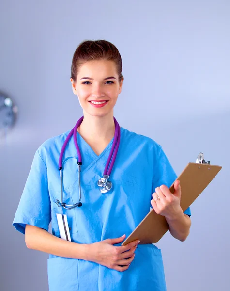 Usmívající se doktorka se složkou v uniformě stojící v nemocnici — Stock fotografie