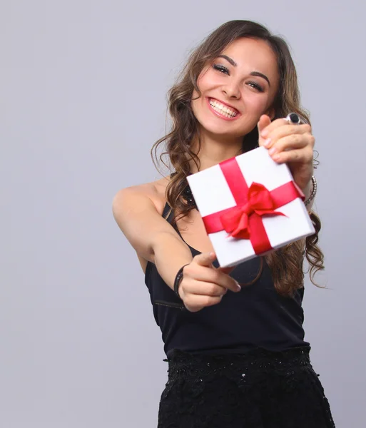 Junge Frau glücklich lächelnd Geschenkbox in den Händen halten, isoliert über grauem Hintergrund — Stockfoto