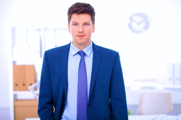 Business man or manager standing against his desk at office — Stock Photo, Image